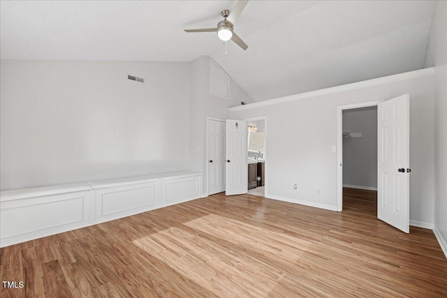 unfurnished bedroom featuring ceiling fan, hardwood / wood-style floors, lofted ceiling, a walk in closet, and a closet