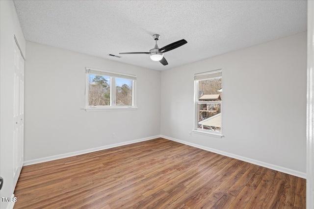 empty room featuring hardwood / wood-style floors, a healthy amount of sunlight, and a textured ceiling