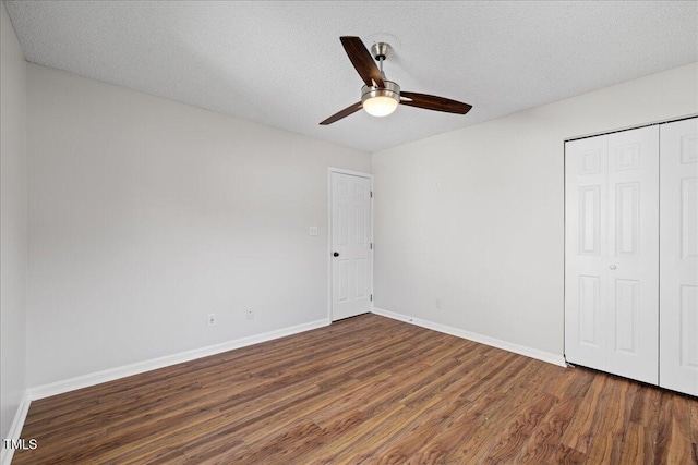 unfurnished bedroom featuring ceiling fan, dark hardwood / wood-style floors, a textured ceiling, and a closet