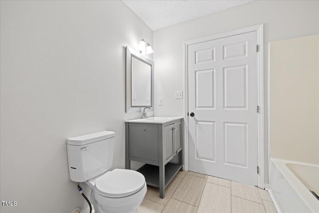 bathroom with vanity, a bath, a textured ceiling, and toilet