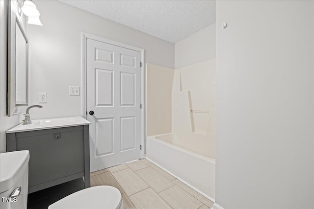 full bathroom with vanity, toilet, a textured ceiling, and bathtub / shower combination