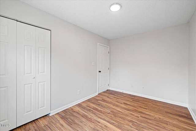 unfurnished bedroom with wood-type flooring, a textured ceiling, and a closet