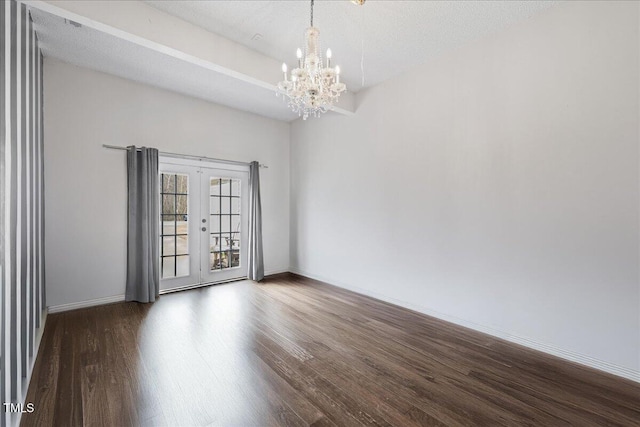 unfurnished room featuring dark hardwood / wood-style flooring, french doors, a textured ceiling, and an inviting chandelier