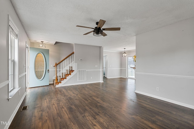 unfurnished living room featuring dark hardwood / wood-style flooring, ceiling fan with notable chandelier, and a textured ceiling