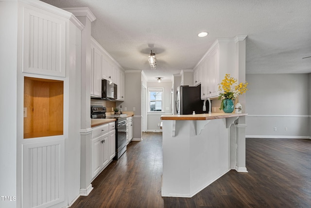 kitchen featuring a breakfast bar, kitchen peninsula, ornamental molding, white cabinetry, and stainless steel appliances