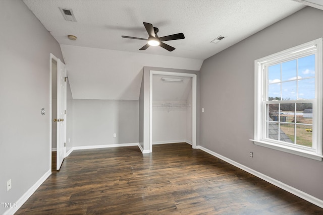 unfurnished bedroom featuring vaulted ceiling, ceiling fan, a textured ceiling, multiple windows, and dark hardwood / wood-style flooring