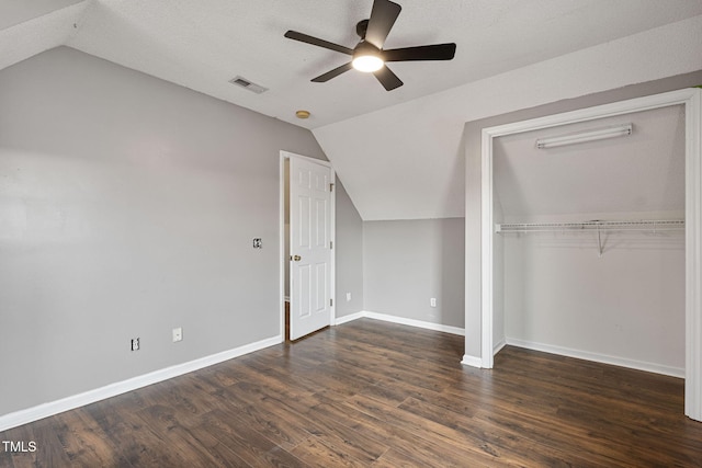 unfurnished bedroom with ceiling fan, dark hardwood / wood-style floors, a textured ceiling, vaulted ceiling, and a closet