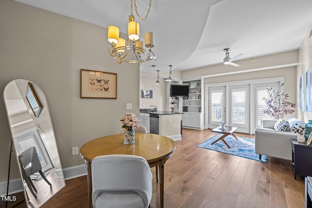 dining space with hardwood / wood-style floors, ceiling fan with notable chandelier, and sink