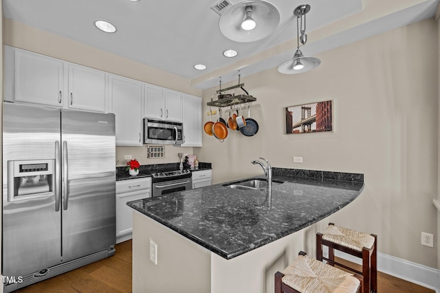 kitchen with kitchen peninsula, stainless steel appliances, sink, decorative light fixtures, and white cabinets