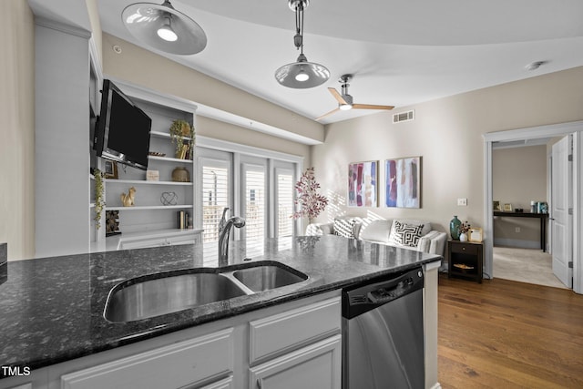 kitchen with dark stone countertops, sink, stainless steel dishwasher, and decorative light fixtures