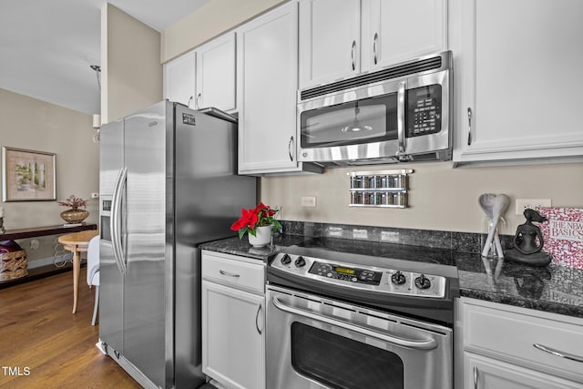 kitchen with white cabinets, appliances with stainless steel finishes, and dark stone counters