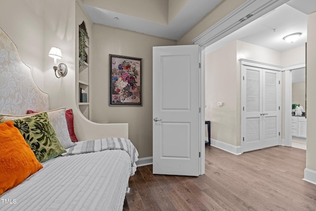 bedroom featuring wood-type flooring, ensuite bathroom, and a closet