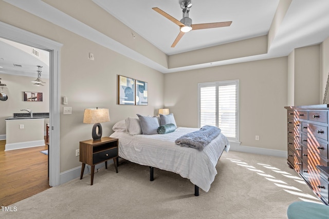 carpeted bedroom featuring ceiling fan and a tray ceiling