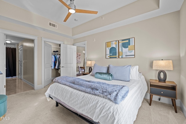 carpeted bedroom with a tray ceiling, ceiling fan, a closet, and a spacious closet