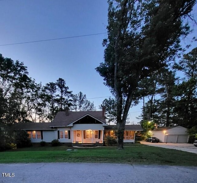 view of front of house with a front yard, concrete driveway, an outbuilding, and a garage