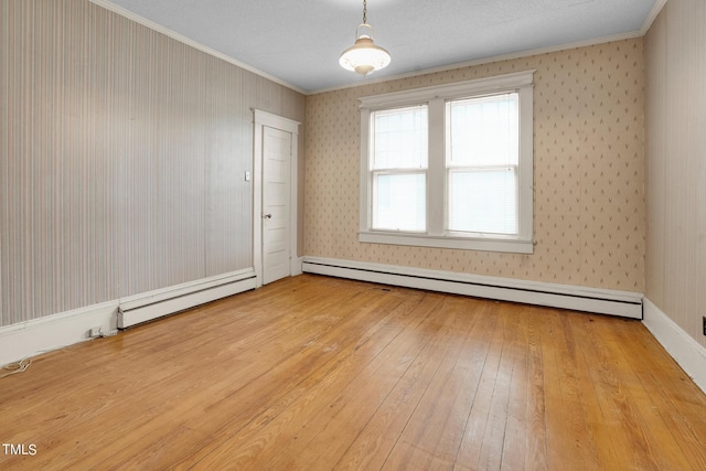 empty room featuring hardwood / wood-style flooring, a textured ceiling, crown molding, and a baseboard radiator