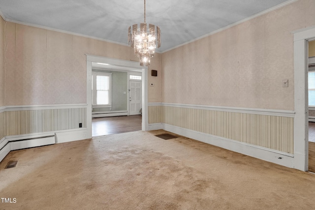 spare room with carpet floors, an inviting chandelier, baseboard heating, and crown molding