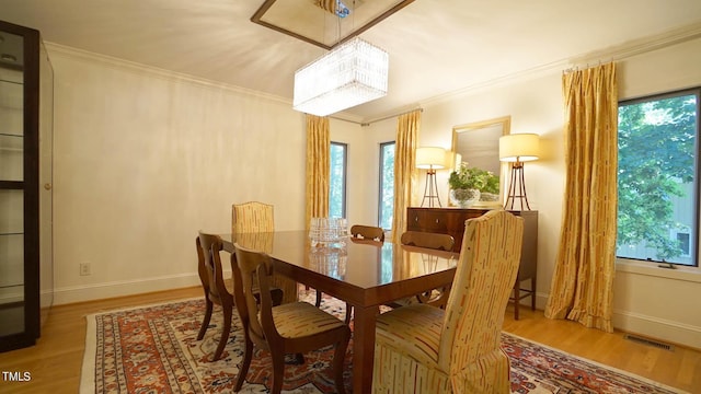 dining space with light wood-type flooring, crown molding, and a wealth of natural light