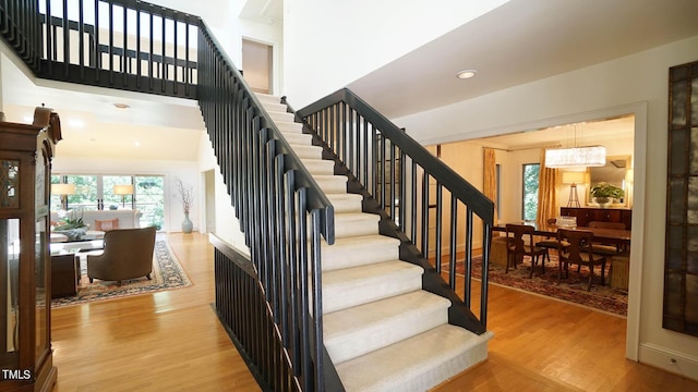 staircase featuring hardwood / wood-style floors and an inviting chandelier