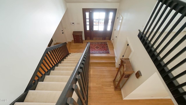 stairway with hardwood / wood-style floors and a high ceiling