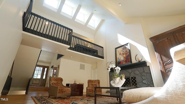 living room with a fireplace, wood-type flooring, and a towering ceiling