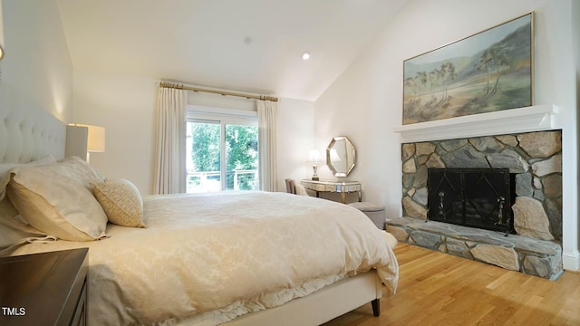 bedroom featuring hardwood / wood-style floors, lofted ceiling, and a fireplace