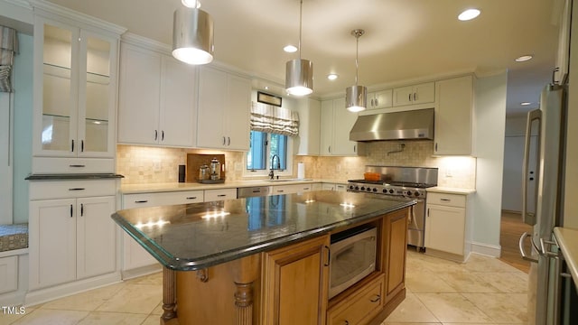 kitchen featuring sink, stainless steel appliances, a kitchen island, dark stone countertops, and white cabinets