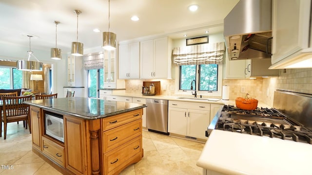 kitchen featuring stainless steel appliances, sink, decorative light fixtures, white cabinets, and a center island