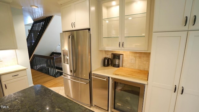 kitchen featuring white cabinets, light wood-type flooring, tasteful backsplash, stainless steel fridge with ice dispenser, and beverage cooler