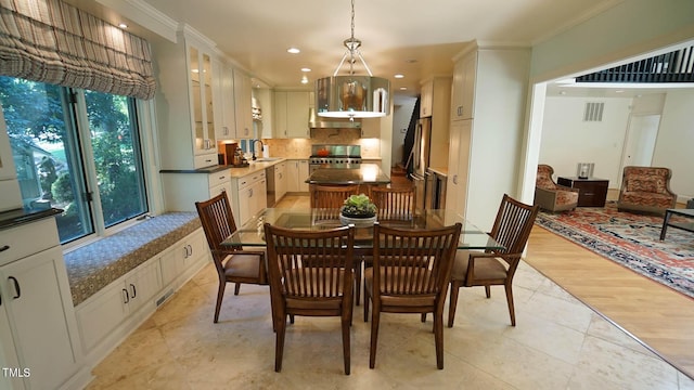 dining room with light wood-type flooring, ornamental molding, and sink