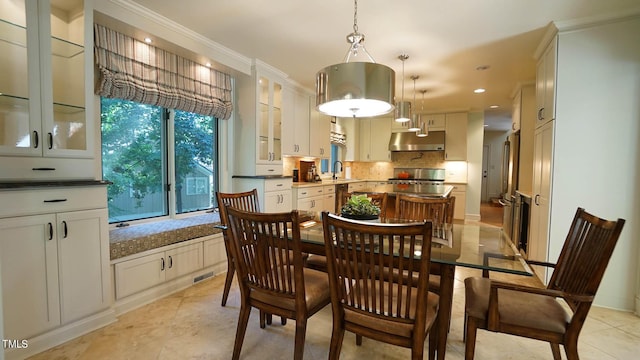 tiled dining room with a wealth of natural light, crown molding, and sink