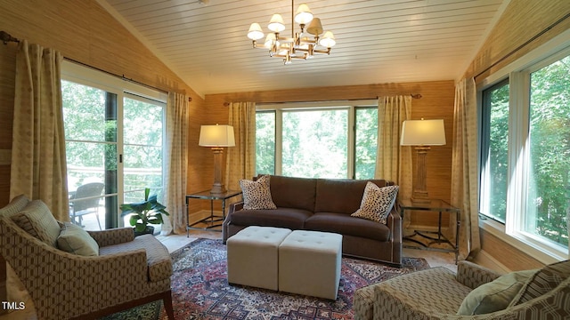 living room with wood walls, plenty of natural light, lofted ceiling, and an inviting chandelier