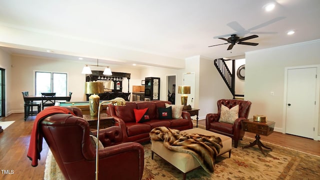 living room featuring hardwood / wood-style flooring, ceiling fan, and ornamental molding