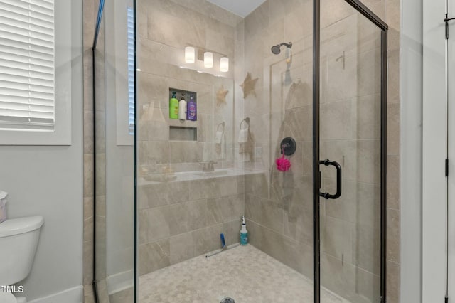 bathroom with a shower with door and toilet