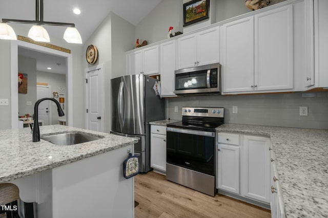 kitchen featuring white cabinets, stainless steel appliances, light stone counters, and sink