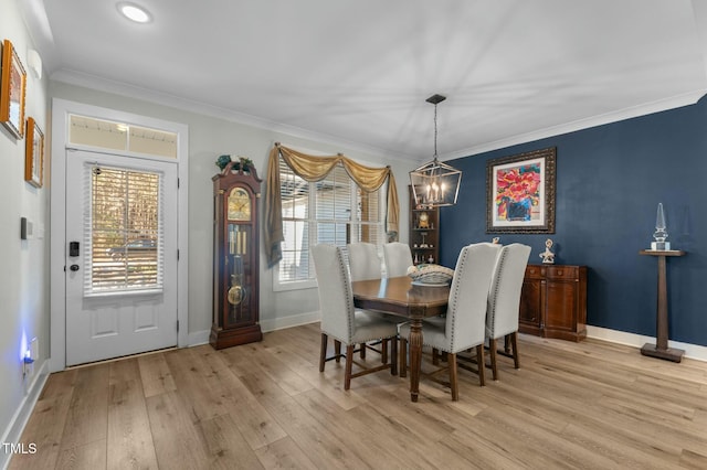 dining area featuring light wood-type flooring, crown molding, and a notable chandelier