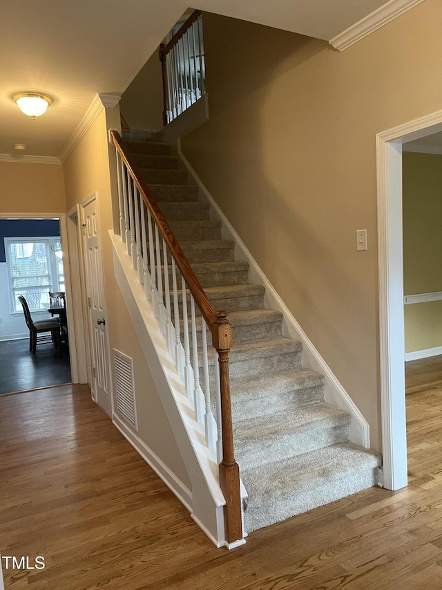 stairway featuring wood-type flooring and ornamental molding