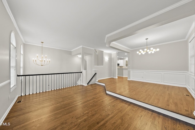 7340 Doverton Ct, Raleigh, NC 27615 - empty room featuring a chandelier, wood finished floors, plenty of natural light, crown molding, and wainscoting