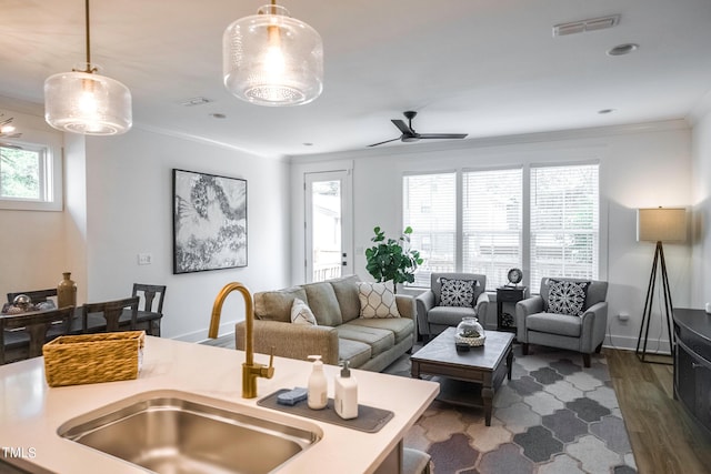 living room with crown molding, sink, ceiling fan, dark hardwood / wood-style floors, and a wealth of natural light