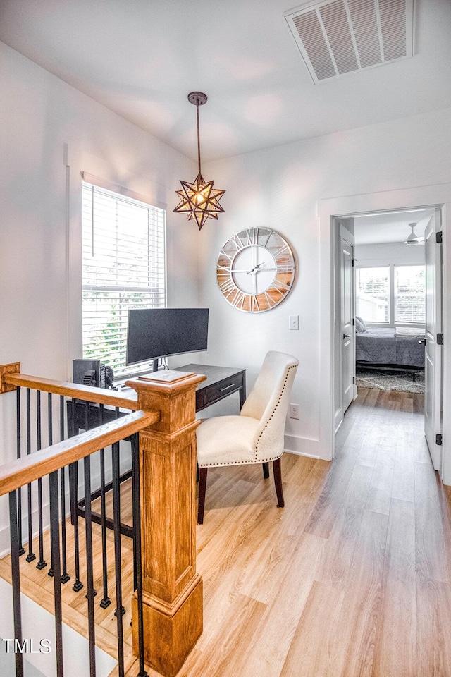 office space with plenty of natural light, an inviting chandelier, and light hardwood / wood-style flooring