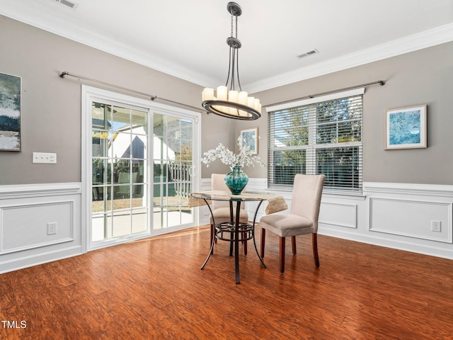 dining area with wood-type flooring, crown molding, and a healthy amount of sunlight