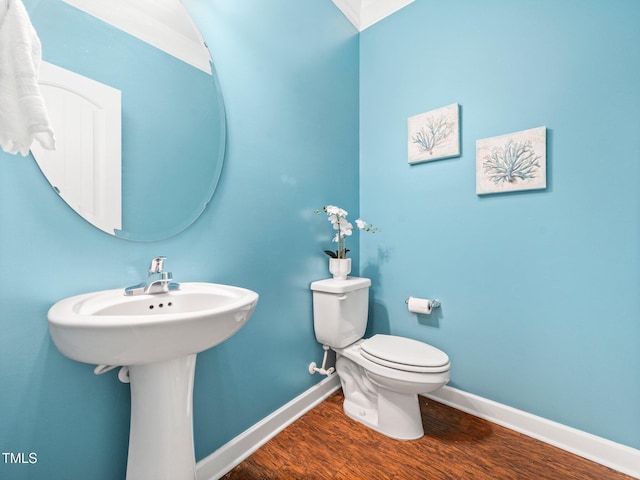 bathroom featuring sink, ornamental molding, wood-type flooring, and toilet