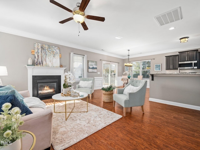 living room with dark hardwood / wood-style floors, ceiling fan, and crown molding