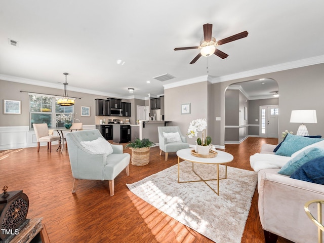 living room with ceiling fan, ornamental molding, and dark wood-type flooring