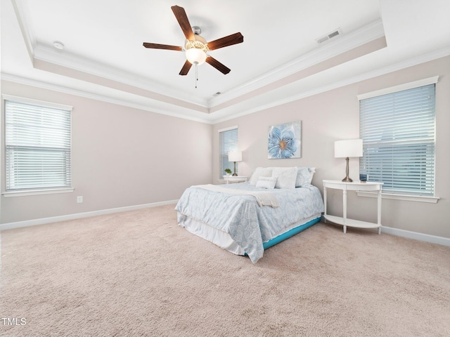 bedroom with carpet flooring, ceiling fan, a raised ceiling, and ornamental molding