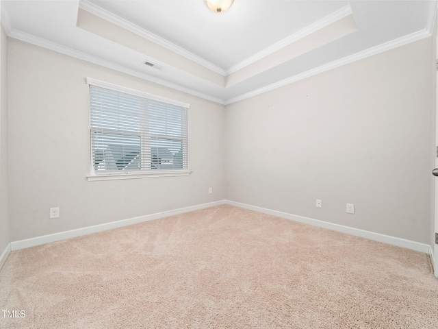 empty room with a tray ceiling, crown molding, and carpet flooring