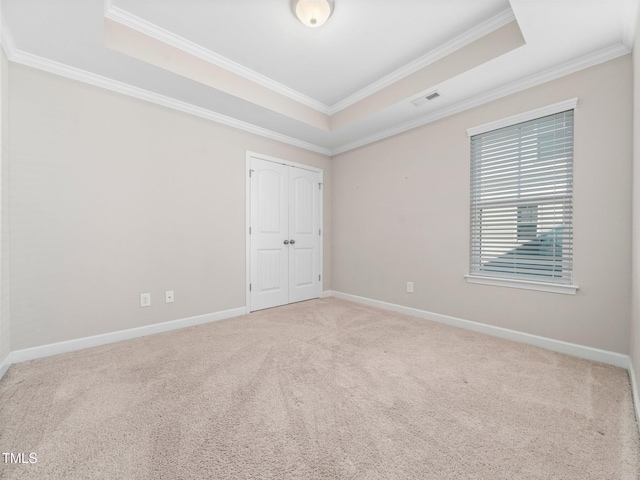 carpeted empty room with a tray ceiling and crown molding