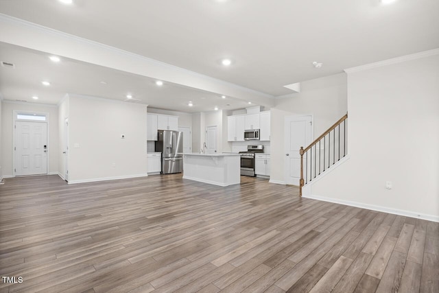 unfurnished living room with sink, light hardwood / wood-style floors, and ornamental molding