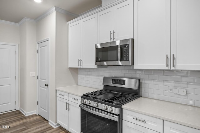 kitchen with white cabinets, appliances with stainless steel finishes, dark hardwood / wood-style floors, and ornamental molding