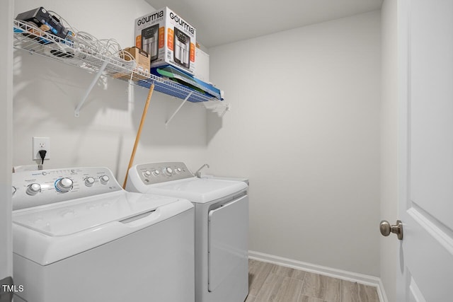 laundry area with washing machine and dryer and light hardwood / wood-style flooring